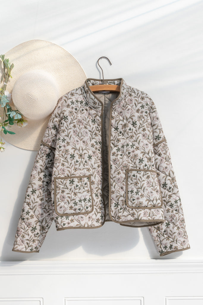 Feminine clothing - a beautiful light weight quilted floral jacket with pockets, dropped shoulders, and a very feminine style. Perfect for spring. Front view on hanger. Amantine. 