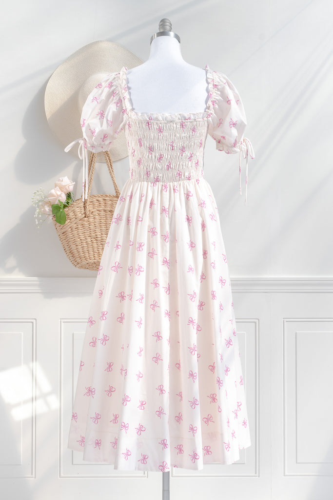 a cottagecore style dress with a very feminine style. it has puff sleeves, ruched bust, and a beautiful pink bow print. back view. 