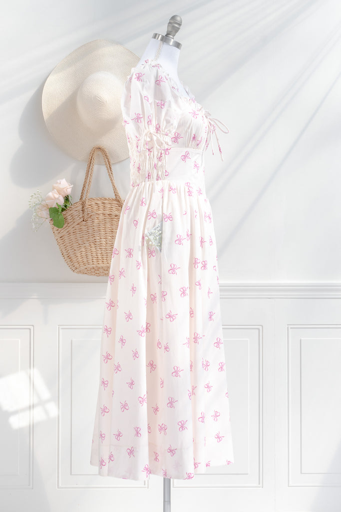 a cottagecore style dress with a very feminine style. it has puff sleeves, ruched bust, and a beautiful pink bow print. side view. 