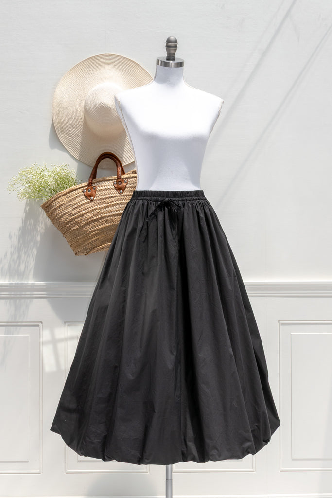 Mannequin wearing a black skirt with a straw bag and hat on a white background