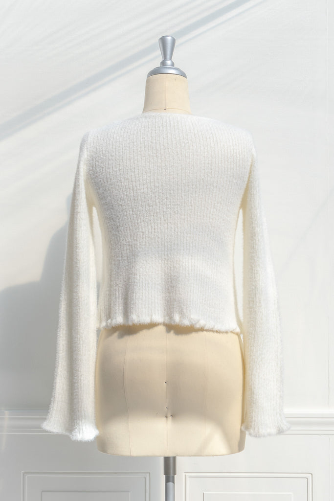 cream colored eyelash cardigan features a v-neckline, long sleeves, and a cropped length. back view. 