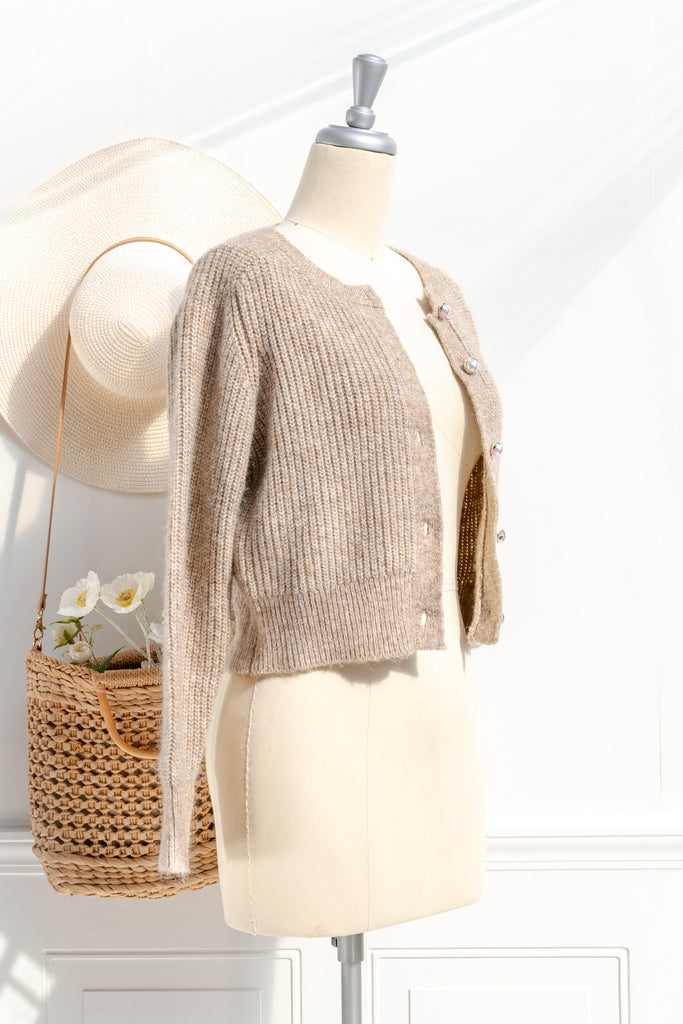 A cozy and comfy cardigan for autumn, the Isobel sweater features faux-pearl buttons, cropped length, a crew neckline, and long sleeves in a soft taupe knit. side view. 