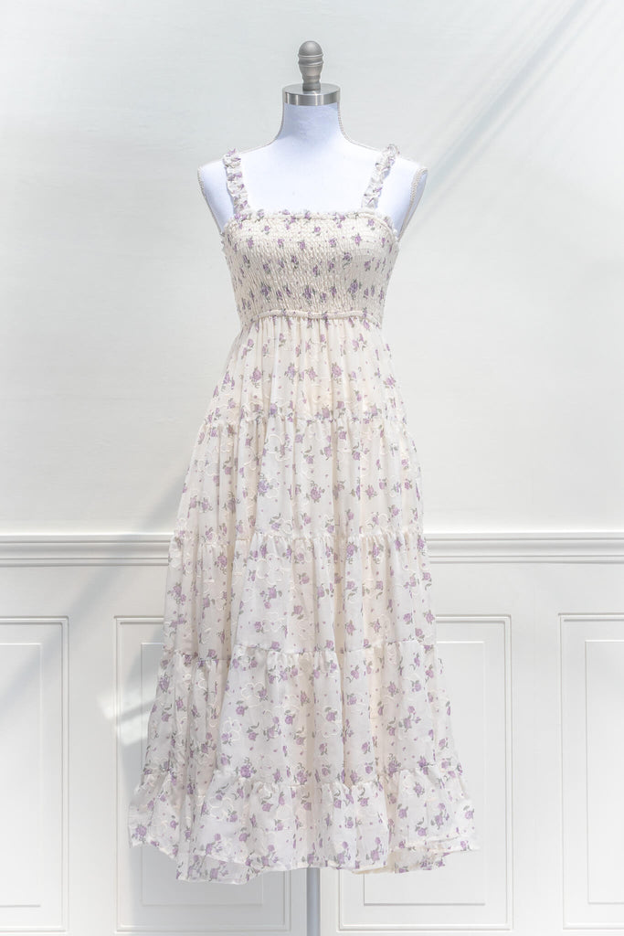 A lovely french style dress - a sun dress, this midi features details such as the ruffled adjustable straps, lavender floral print on cream cotton, full length skirt, and a smocked elastic bodice for a comfortable, flattering fit. front view. 