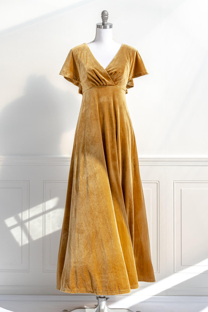 long yellow mustard velvet holiday dress - featuring a feminine cottage core silhouette, v neckline, short sleeves, and long skirt. billowing in the wind view - amantine.