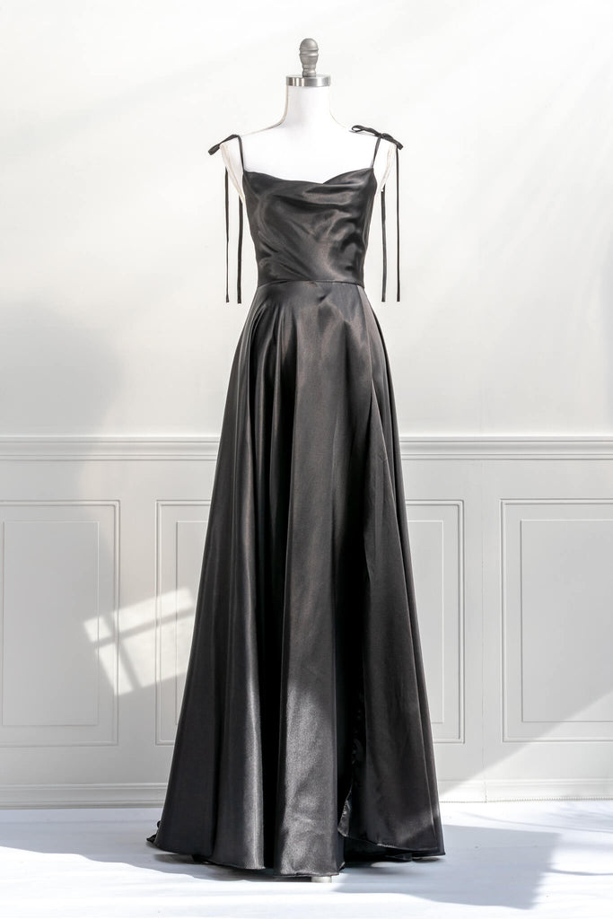 french elegant long black gown - made of a silky and shiny black fabric, with spaghetti straps, and a french feminine cowl neckline. features a side slit. front view - amantine.   