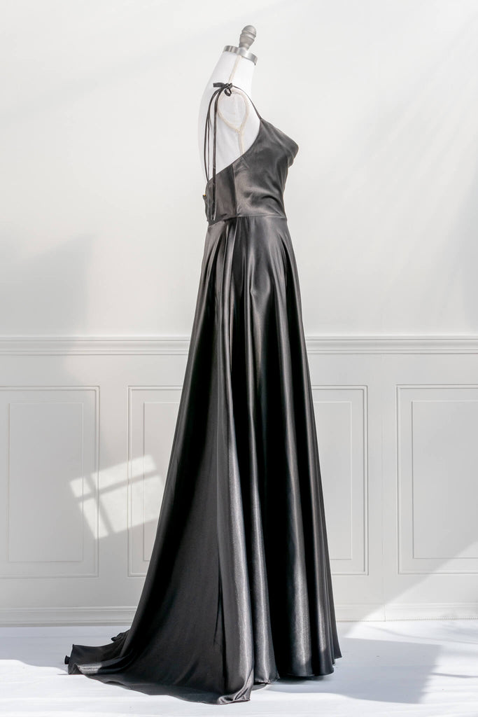 french elegant long black gown - made of a silky and shiny black fabric, with spaghetti straps, and a french feminine cowl neckline. features a side slit. side view - amantine.   
