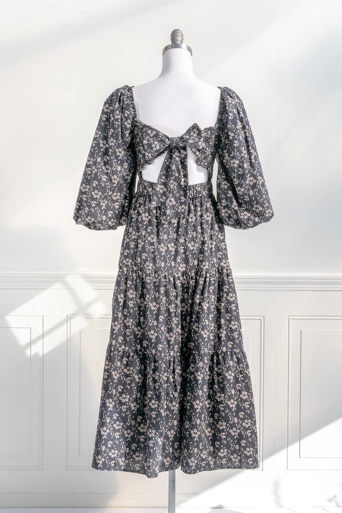 french dresses - dress with a smocked bodice, open-tie back, 3/4 length puffed sleeves, and a delicate vintage style taupe floral print on black. back view. Amantine. 