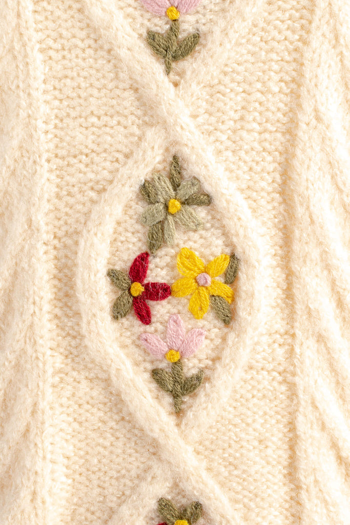 view of cable knit and small green, yellow, and red flowers embroidered. feminine sweaters from amantine. 