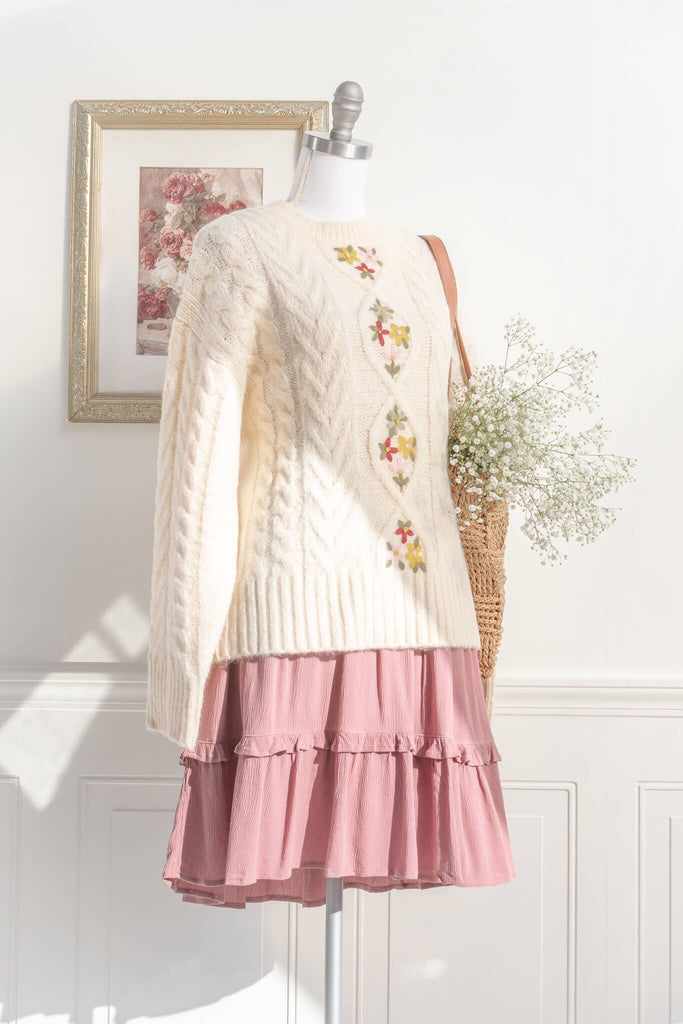 cottage core and feminine tops. an oversized knit style, long sleeves, cable-knit, and lovely embroidered florals in a cream fabric. styled with a pink french style dress view. amantine. 