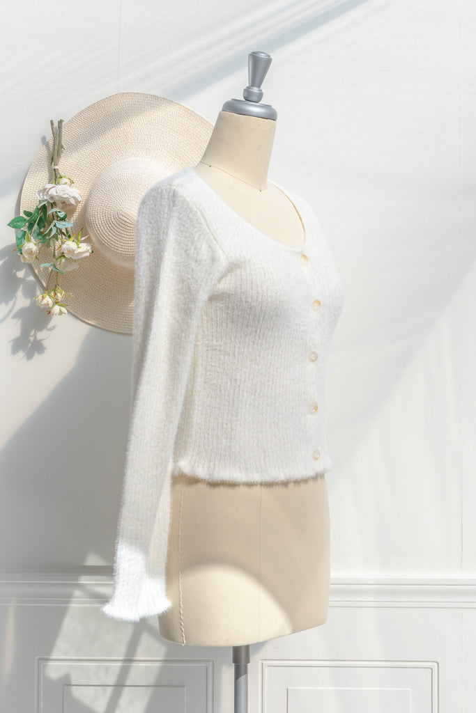 cream colored eyelash cardigan features a v-neckline, long sleeves, and a cropped length. side view. 