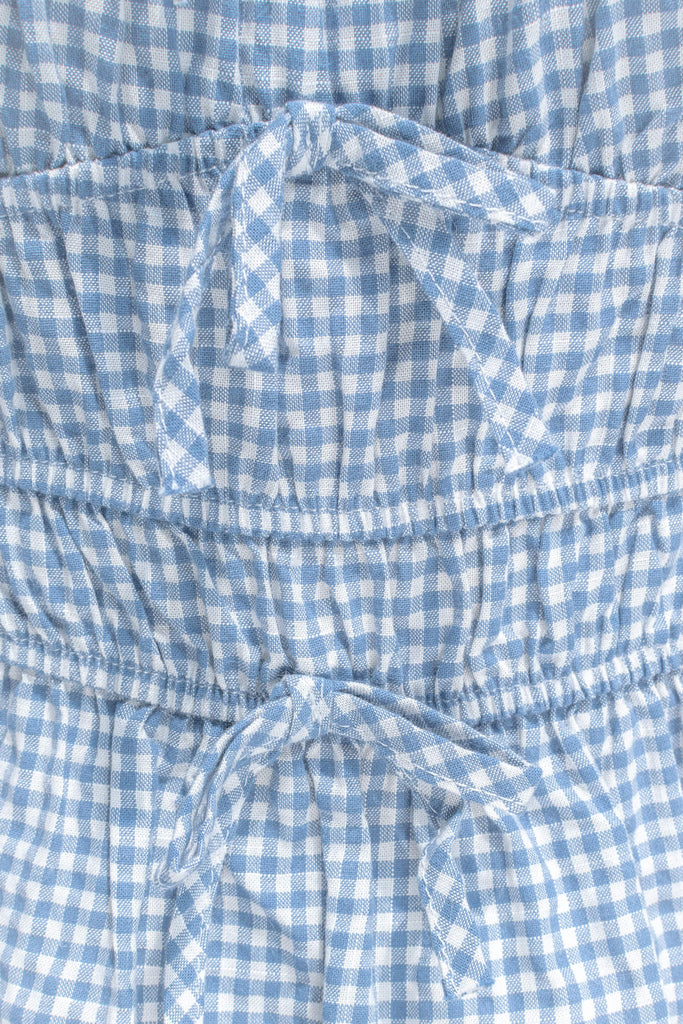 feminine clothing - a white and blue gingham peplum top with a sweetheart neckline and puff sleeves. perfect for summer activities or to feel romantic. front bow view. amantine.