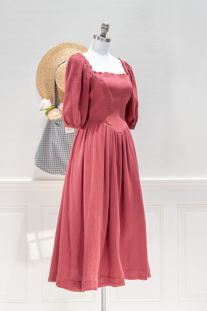 feminine french style dress on a mannequin with a straw hat and bag in the background