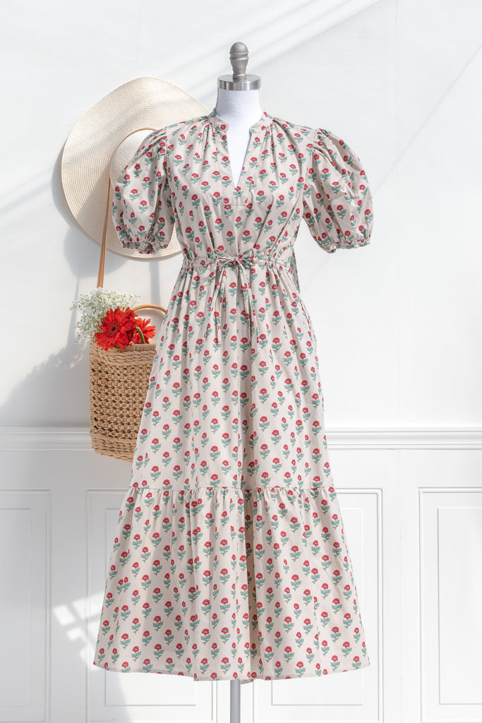 french dresses - a cottagecore style french girl dress in cotton, featuring a taupe fabric with stylized red and green florals. puff sleeves, v neck, drawstring waist and a line silhouette. front view. 