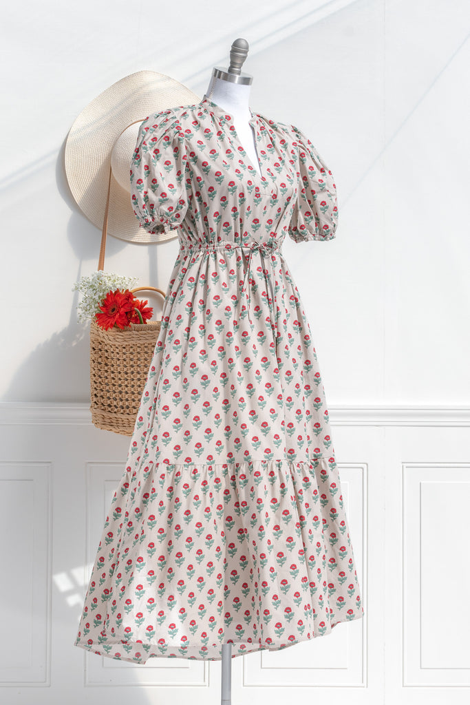 french dresses - a cottagecore style french girl dress in cotton, featuring a taupe fabric with stylized red and green florals. puff sleeves, v neck, drawstring waist and a line silhouette. side view. 