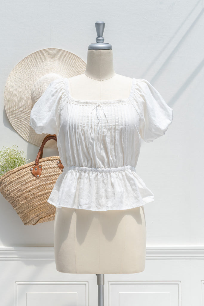 White blouse on a mannequin with a straw hat and bag against a white background. French girl style. 