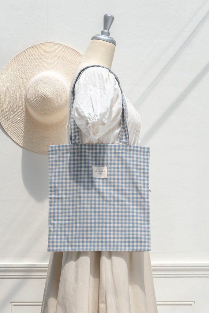 Mannequin wearing a blue checkered bag with a beige hat on a white background