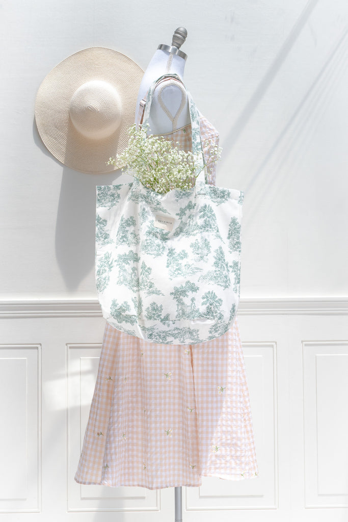 Mannequin wearing a floral dress with a straw hat and flowers on a white background