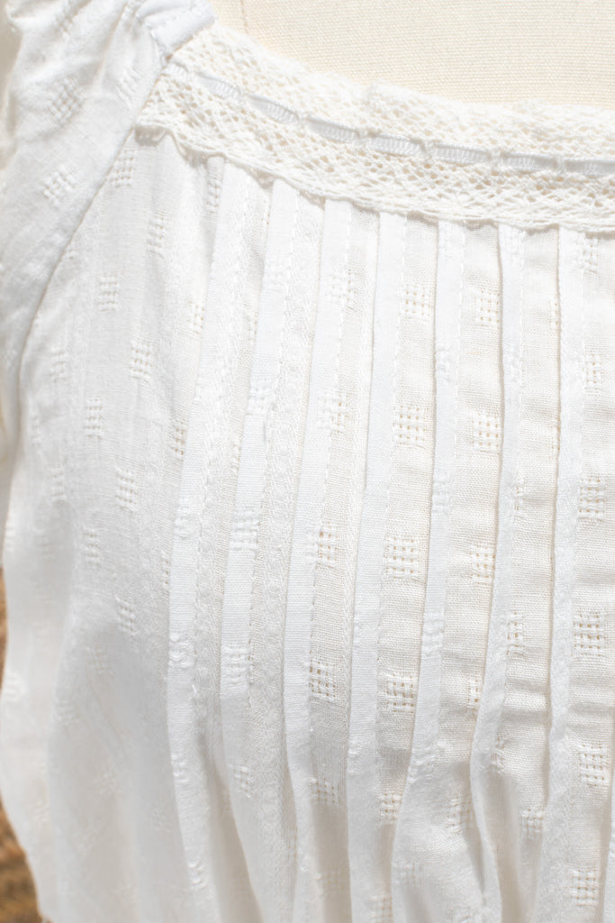 Close-up of a white textured fabric garment on a mannequin.