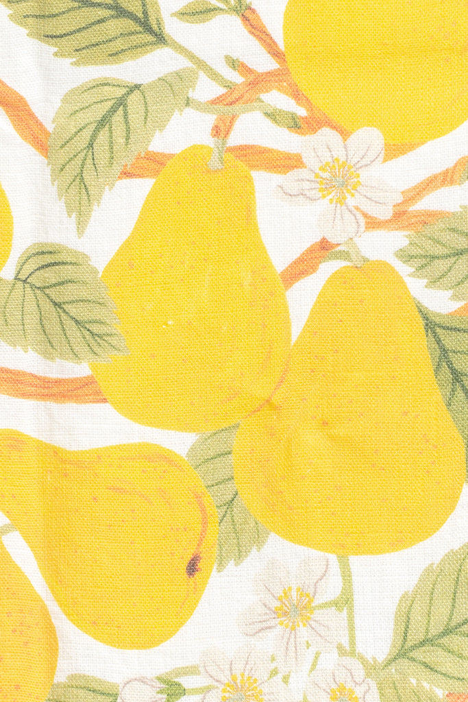 a pear print french kitchen towel. gifts for francophiles. up close view of yellow pear and pear blossom on linen fabric. 