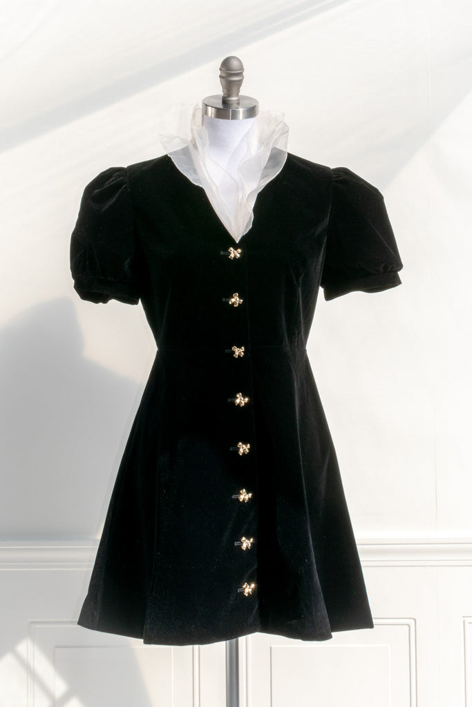 black velvet mini dress for the holidays. Unique velvet dress with cute gold buttons, and unique white ruffle neck. Cute dress for holidays. Front view. 