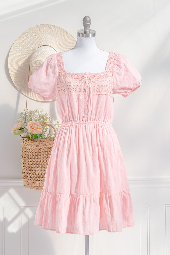 Pink summer dress with lace bodice, puff sleeves, and button-down front, styled with a straw hat and woven bag. amantine dresses. 