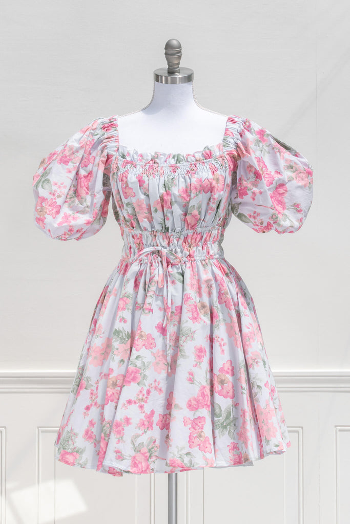 cottagecore mini dress for spring. a floral dress of pink on blue fabric with puff sleeves and front bow. front view. 