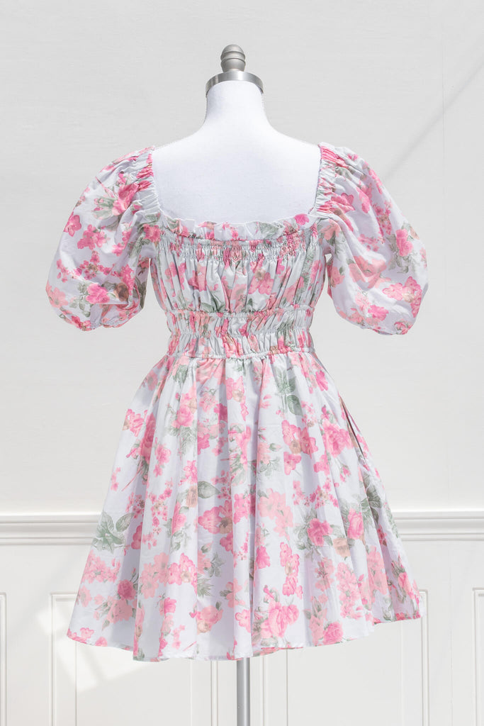 cottagecore mini dress for spring. a floral dress of pink on blue fabric with puff sleeves and front bow. back view. 
