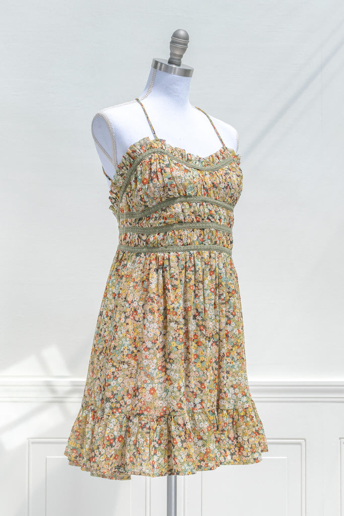 vintage style sun dresses - a mustard and green floral mini dress with straps. quarter side view. 