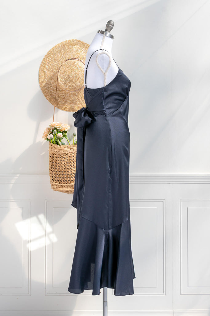 Beautiful wedding guest and formal dress in navy blue. French style feminine and romantic dress with straps, slit, and a bow. side view. Amantine dresses. 