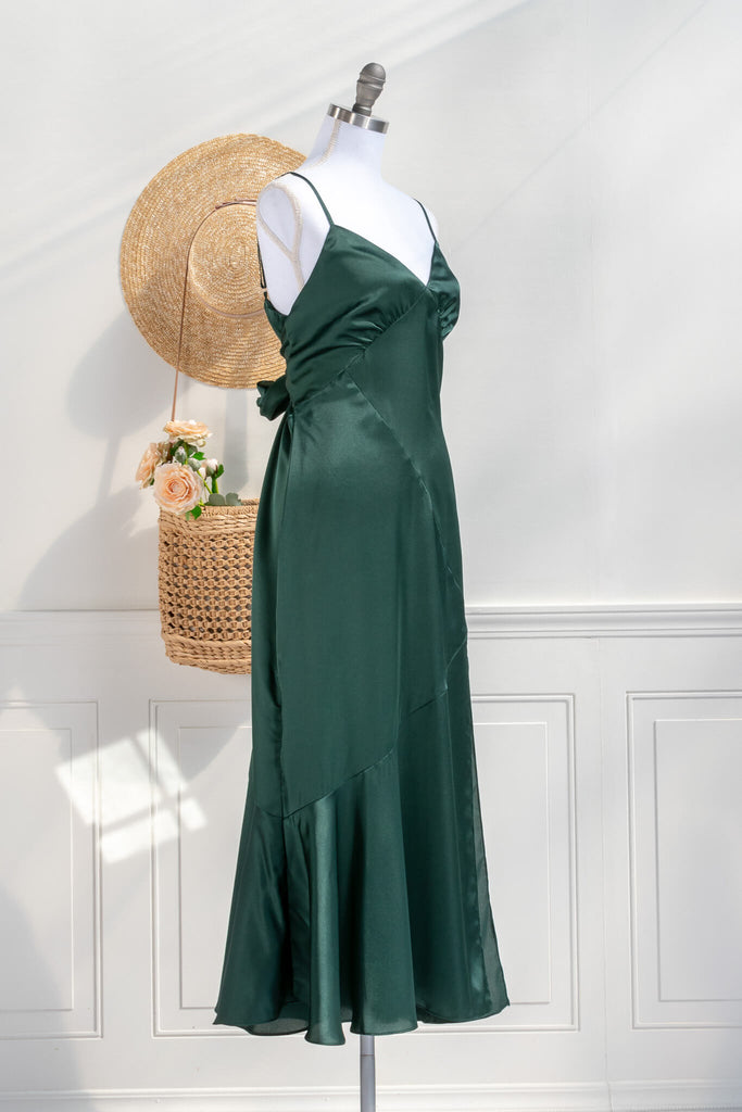 Beautiful wedding guest and formal dress in emerald green. French style feminine and romantic dress with straps, slit, and a bow. Front view. Amantine dresses. 