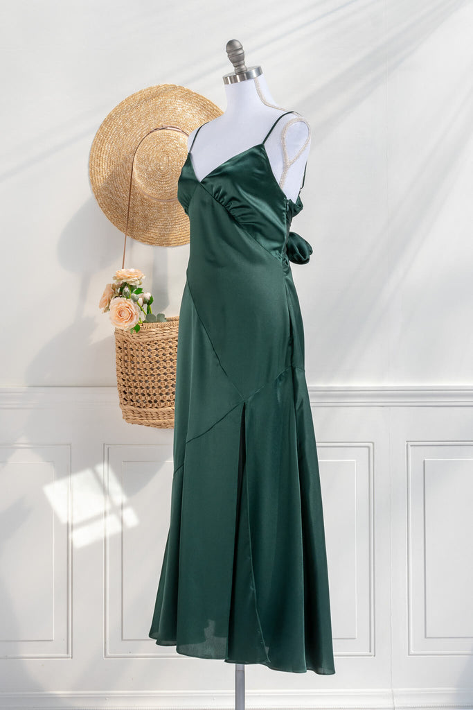 Beautiful wedding guest and formal dress in emerald green. French style feminine and romantic dress with straps, slit, and a bow. side view. Amantine dresses. 