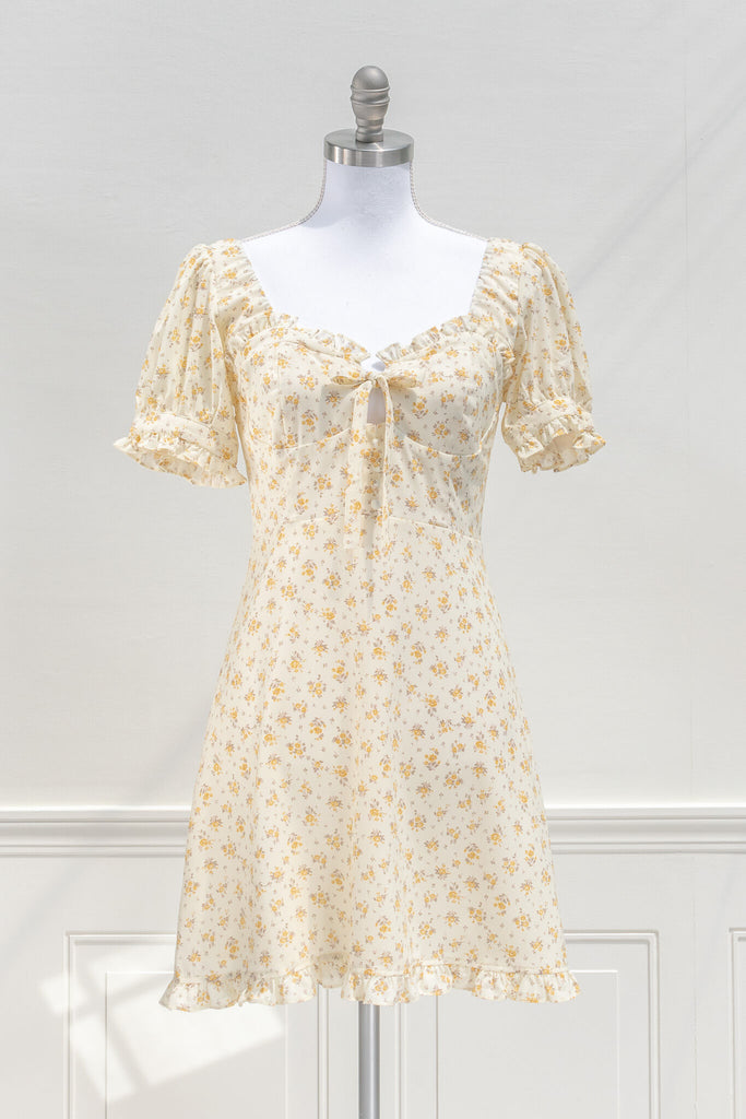 cottagecore dresses for spring - a mini yellow floral dress with a front bow, sweet heart neckline, and short sleeves. front view. amantine. 