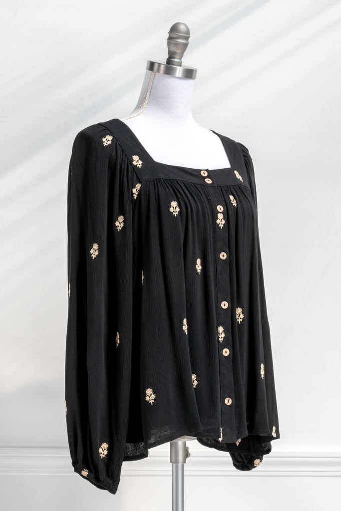Vintage fashion style from Amantine - a black button down blouse with gold thread floral details, square neckline and long sleeves - quarter view